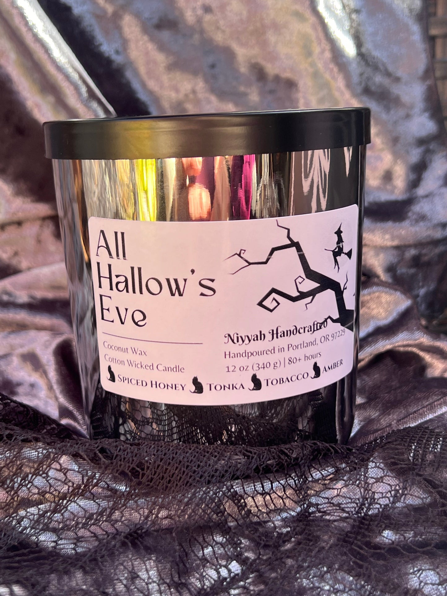 silver jar candle with white label on gray velvet and lace