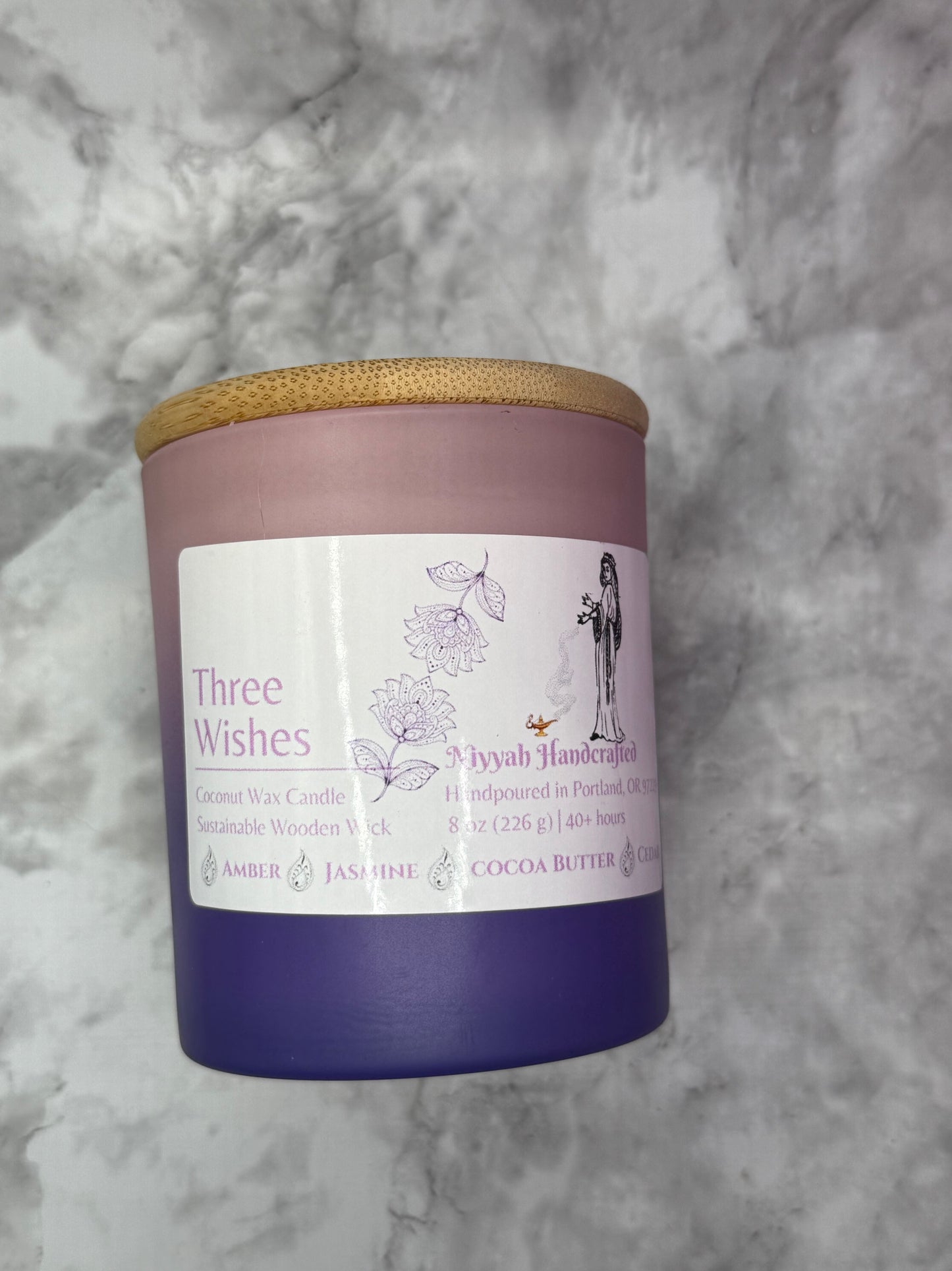 Pink to purple ombre cylinder candle against grey marble background