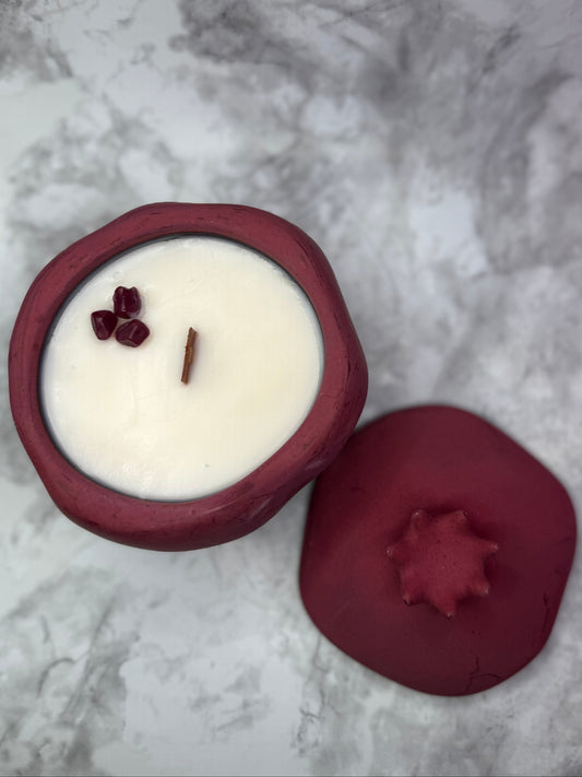 Pomegranate shaped candle against a white marble background 