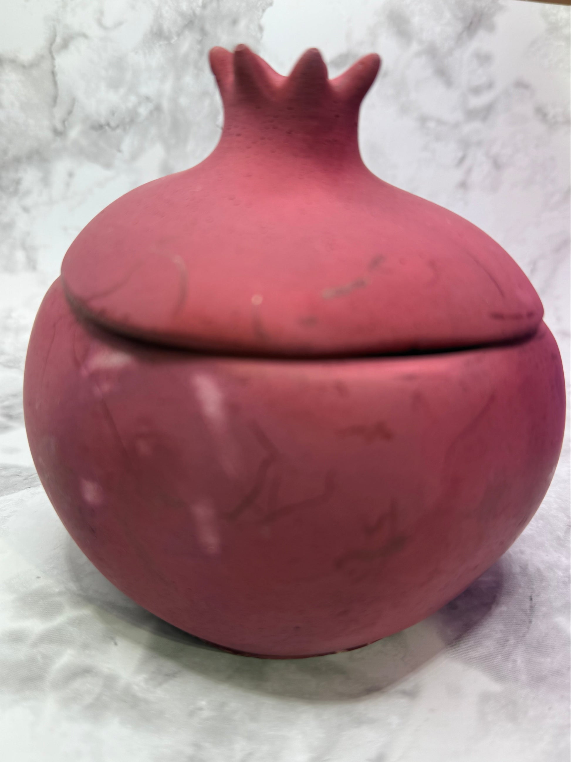 Pomegranate shaped candle against grey marble background 