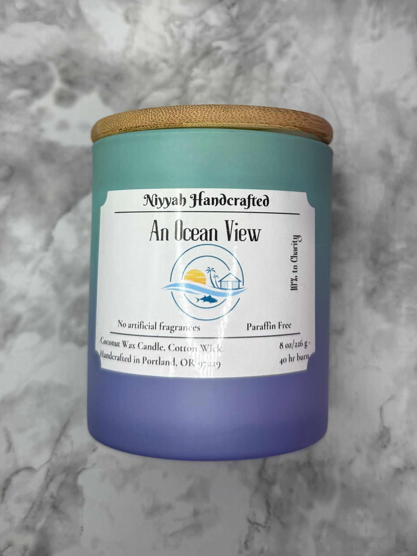 Aqua to blue ombre cylinder candle against grey marble background